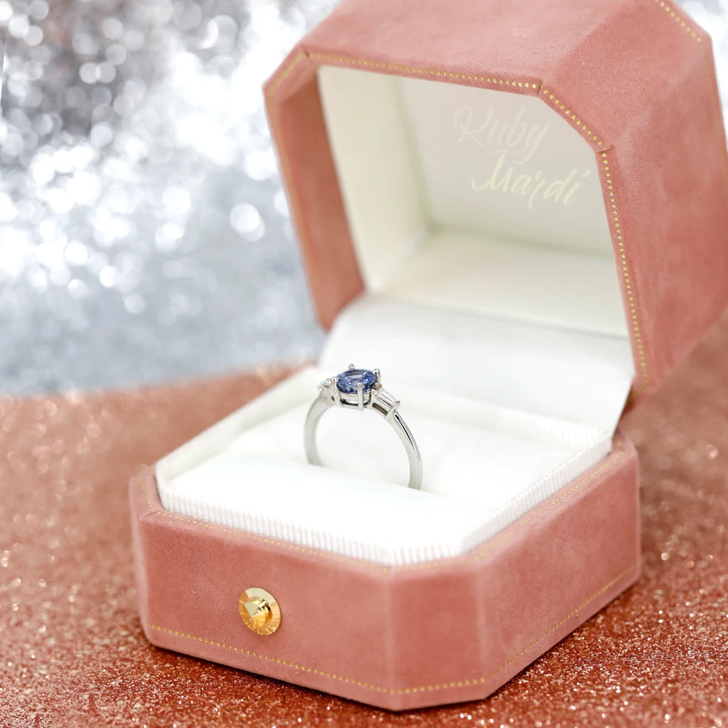 This alternative engagement ring with a round sapphire and diamond set in white gold is a custom creation by jeweller Justine Quintal. Seen here in a pretty pink box, this bridal jewelry piece is exclusive to Ruby Mardi, Montreal's best jewelry store featuring independent Canadian jewelry designers.