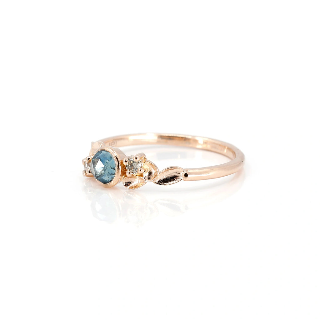 This delicate alternative engagement ring is made in Montreal by artisan jewelry maker Émigé. Made in rose gold with Rose cut Montana sapphire and bezel set, this ring is adorned with champagne diamonds. Custom-made in Canada, this bridal jewelry is available for sale at the fine jewelry store Ruby Mardi.