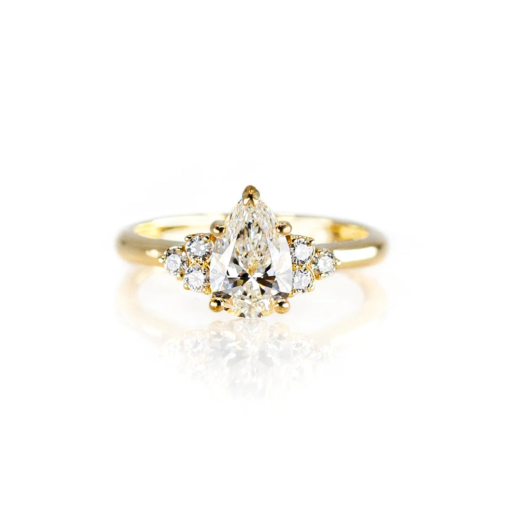 The Ruby Mardi jewelry store presents the engagement ring with a pear-shaped laboratory diamond with small side gems, mounted on yellow gold. Made by independent jewelry artists from Montreal, specialized in bridal rings and fine jewelry.