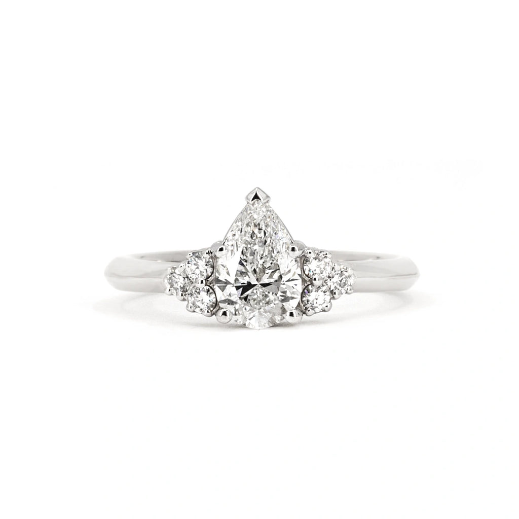 The Ruby Mardi jewelry store presents the engagement ring with a pear-shaped laboratory diamond with small side gems, mounted on white gold. Made by independent jewelry artists from Montreal, specializing in bridal rings and fine jewelry.