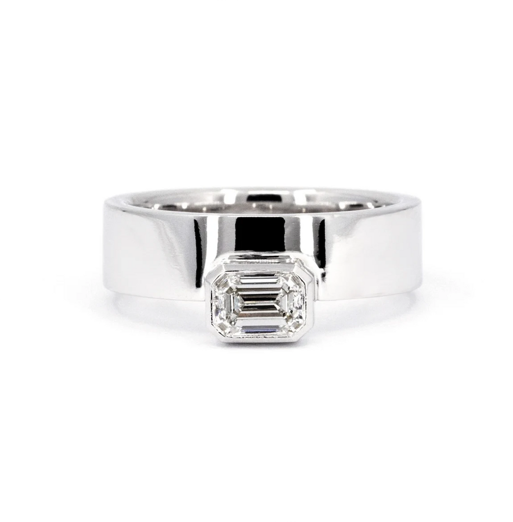 White gold ring with an emerald-cut diamond in a bezel setting, displaying an edgy and boxy style. This exceptional creation by Bena Jewelry, an independent designer based in Canada, embodies boldness and elegance. A fine piece of jewelry that defines the statement. Available for purchase at Ruby Mardi, the jewelry store and jewelry gallery in Montreal, specializing in unisex jewelry.
