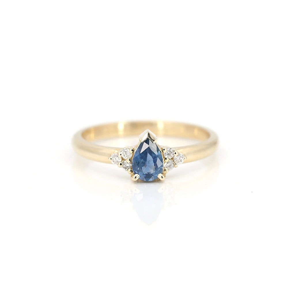 Blue sapphire yellow gold engagement ring with diamond accents, photographed on a white background. Handmade in Toronto by Arsaeus Designs, and available in Montreal at fine jewelry store Ruby Mardi. One-of-a-kind gold ring.