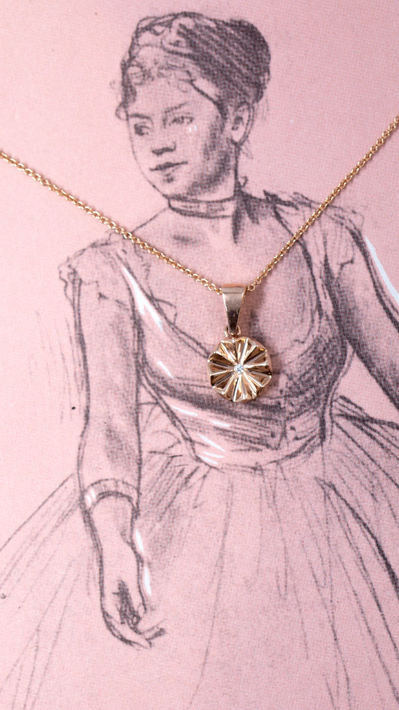 Rose Gold round pendant evoking a flower with a central natural diamond, seen photographed in front of a drawing from French artist Degas showing a dancer.