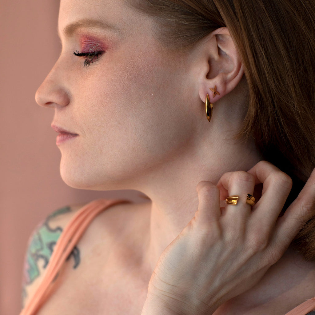 A young and rock lady is wearing many gold vermeil jewels by Montreal brand Bena Jewelry. All these statement pieces (earrings and ring) are available at jewellery store Ruby Mardi in Little Italy.