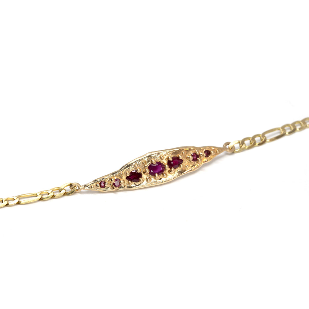 An organic handmade gold bracelet with gold granules and encapsulated rubies. Find this piece of jewelry by Meg Lizabet at Ruby Mardi, a fine jewelry store located in Montreal's Little Italy.