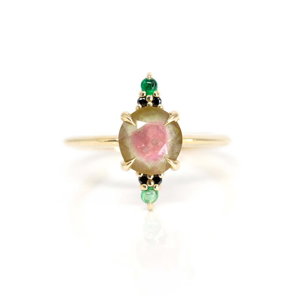 A true work of art seen in close up : a yellow gold ring featuring a central watermelon tourmaline, emerald and black diamonds. A delicate and non conventional ring. Stunning colours for an unique engagement ring.