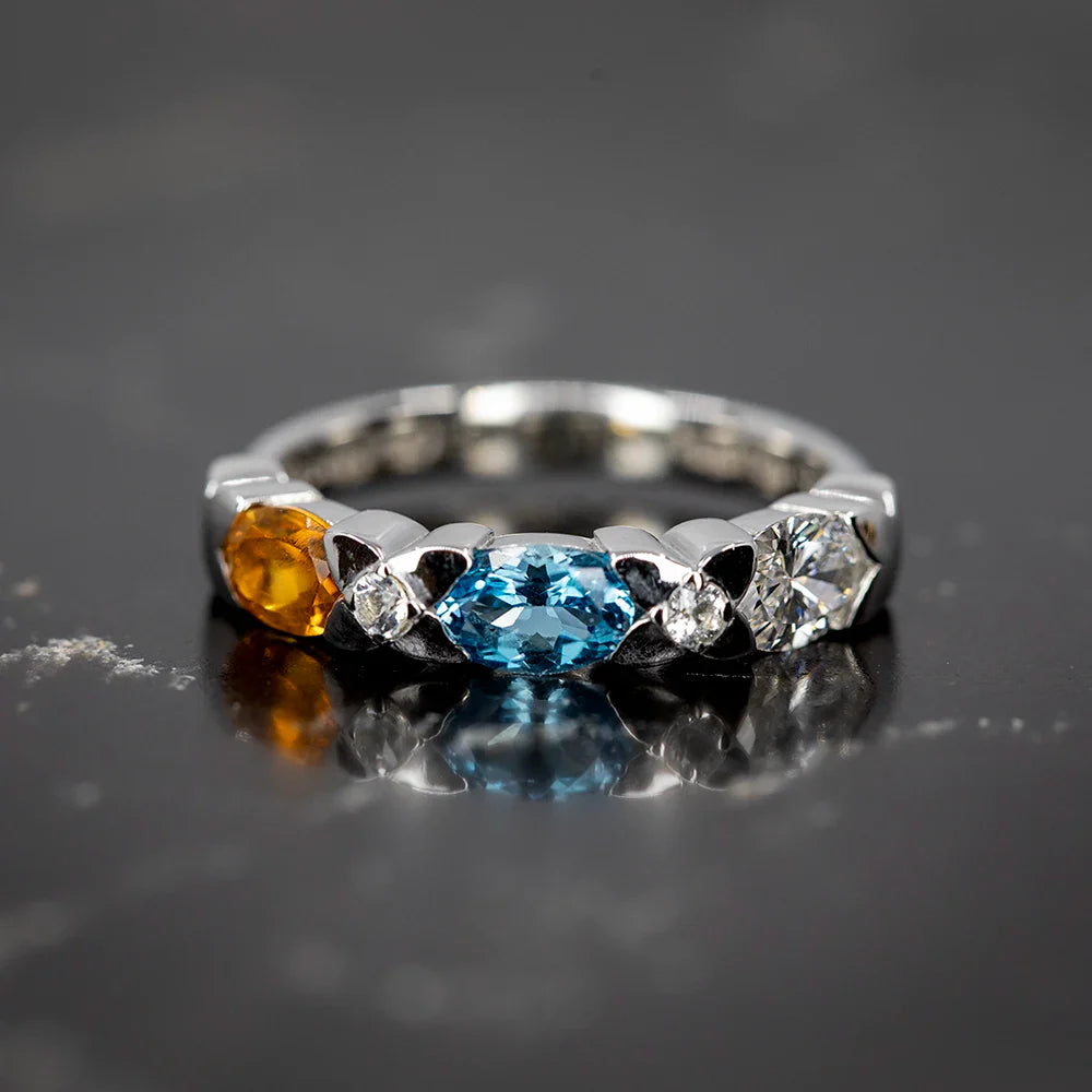 White gold Myosotis ring by Fleurs Sauvages Qc featuring a marquise blue topaz, a round citrine and two diamonds set in a sculpted floral-inspired band. Handmade designer jewelry available at Ruby Mardi Montreal.