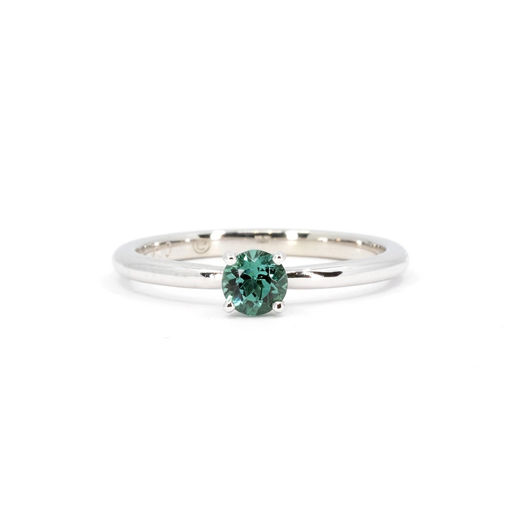 Product photography of a classic white gold solitaire engagement ring feature a beautiful natural round green tourmaline set with 4 rounded prongs. This classic, elegant and timeless engagement ring or right hand ring was made in Montreal by Atelier Emige and is available at Canadian jewelry store Ruby Mardi.