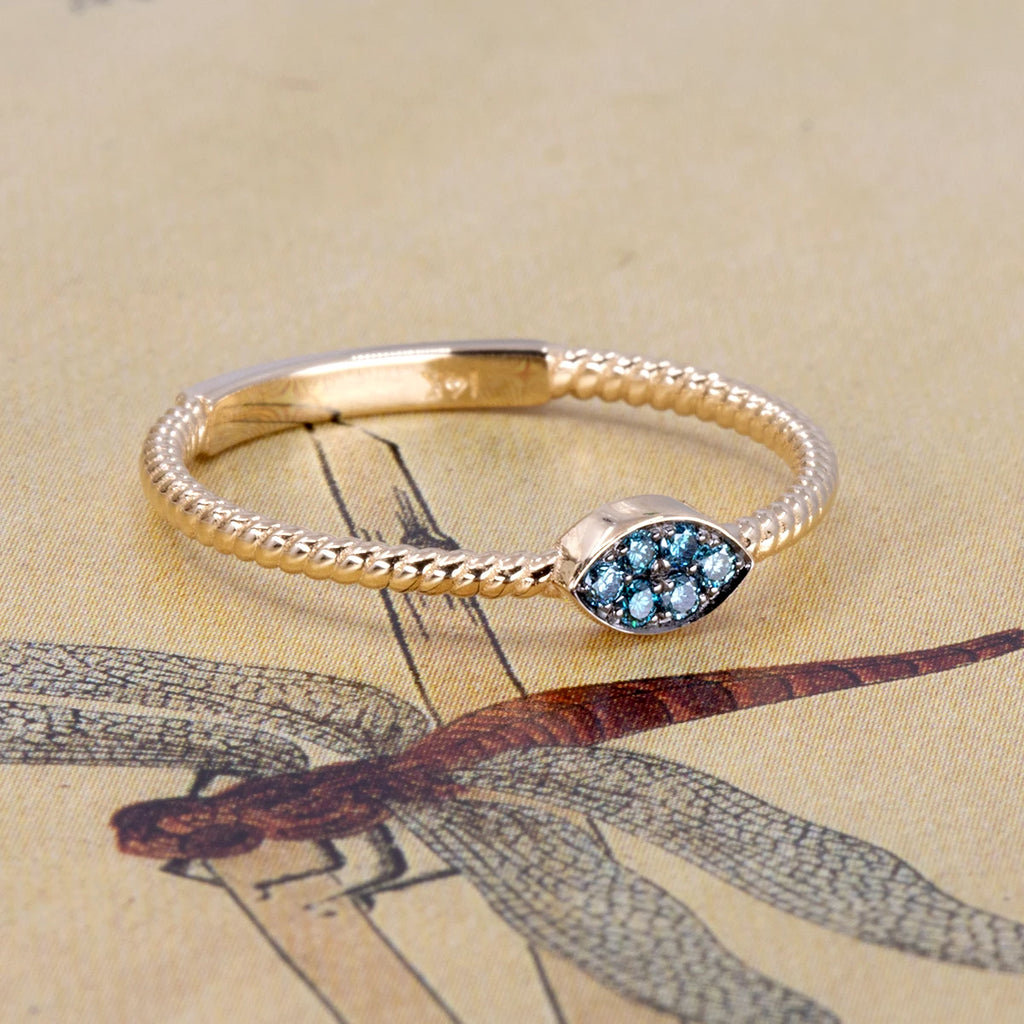 Alizé ring in 14k yellow gold with pavé-set blue diamonds and twisted band, designed by Oleg Leybman in Toronto. Shown on a vintage dragonfly illustration, available at Ruby Mardi, Montreal.