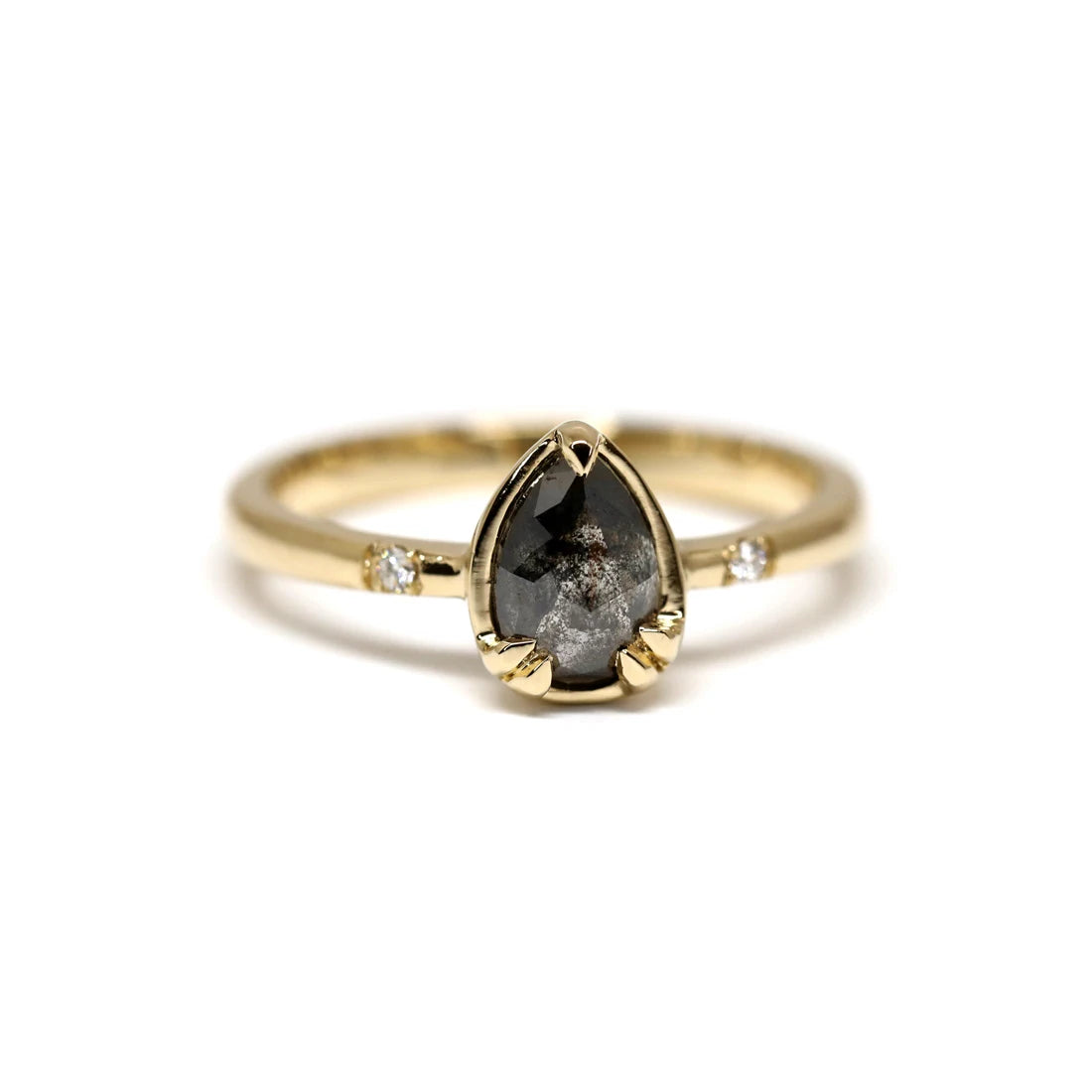 Black diamond - or salt and paper diamond - alternative engagement ring set in yellow gold with white natural diamond accents. This ring was handcrafted in Canada by Yuliya Chorna and is seen photographed on a white background. Find it at Ruby Mardi, an upscale jewelry boutique that sells one-of-a-kind designer work, as Gem Breakfast does in the USA.