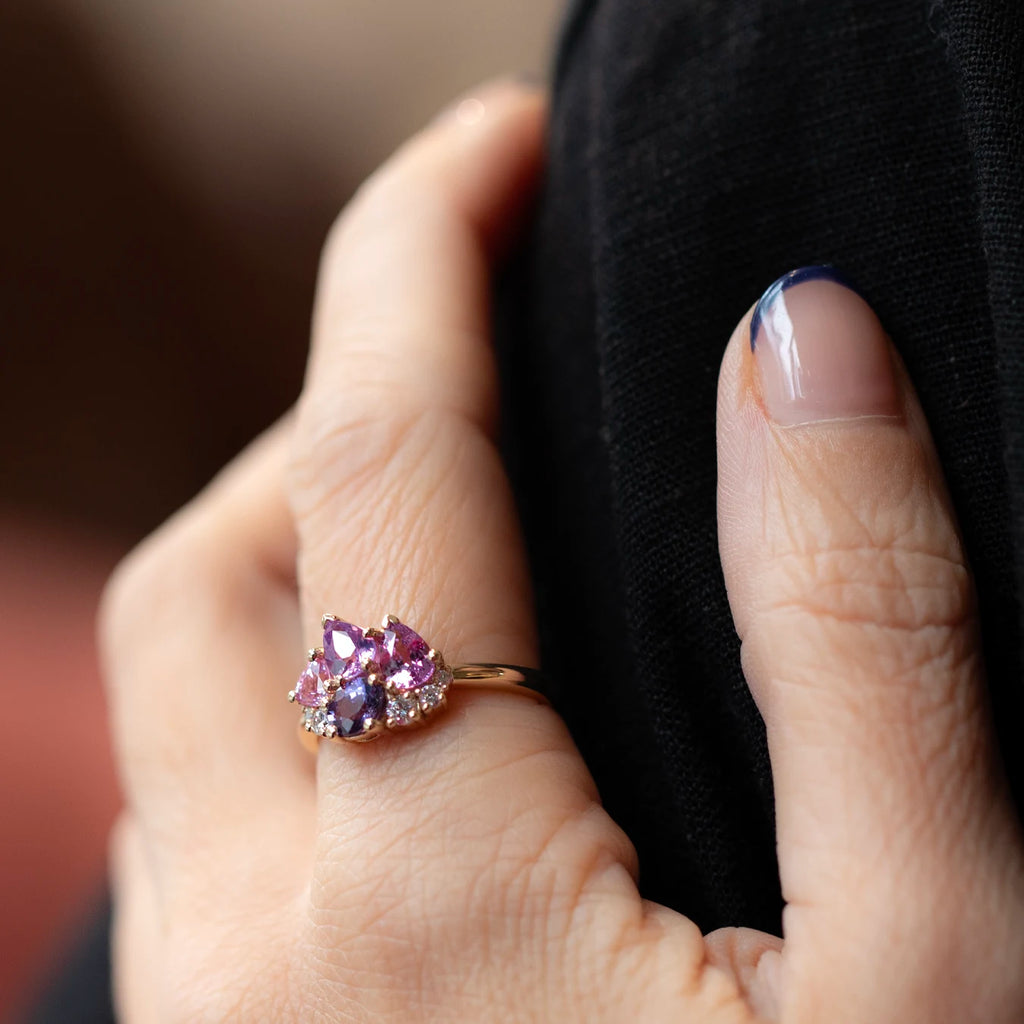 Petal Soufflé cluster ring by Ruby Mardi photographed on the hand in natural light. The 14k yellow gold design features pink, lilac and purple sapphires with bright lab-grown diamonds, showing the scale and soft sparkle when worn.