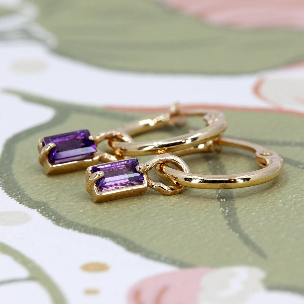 Pair of gold hoops with dangling rectangular amethyst gemstones, handcrafted jewelry by Nadia Werchola for Ruby Mardi.