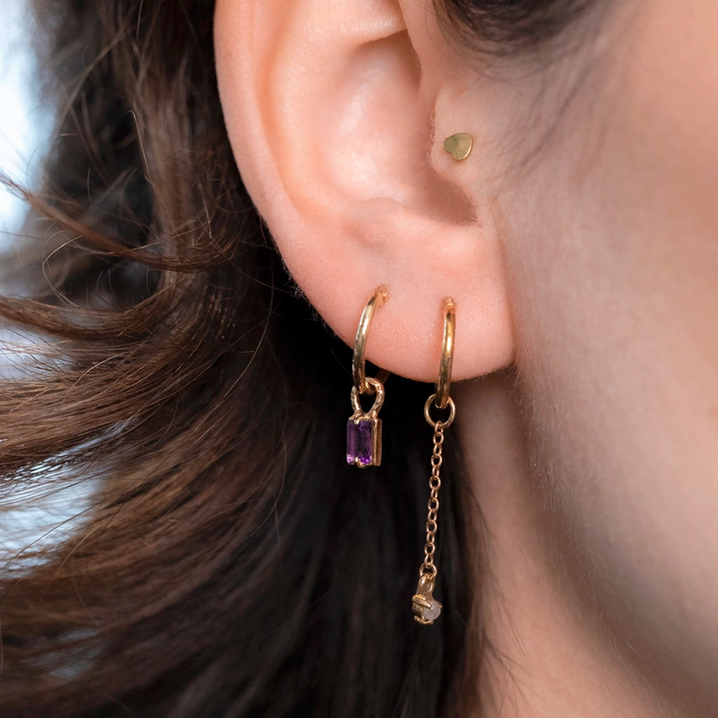 Worn view of amethyst drop hoop earrings in 10k gold, layered with other earrings, Ruby Mardi Montreal.