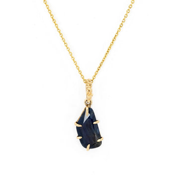 Amorphous blue sapphire pendant in 14k yellow gold with unique organic details, designed in Meg Lizabet's Baleal signature style, available at Ruby Mardi, Montreal.