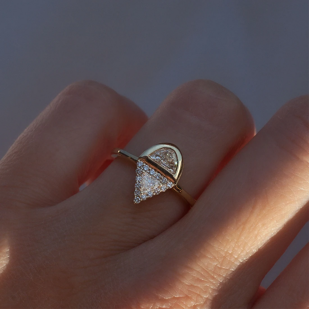 Geometric diamond engagement ring with trillion and half-moon diamonds worn on hand, yellow gold halo setting, designed by Anastassia Sel, available at Ruby Mardi, Montreal.