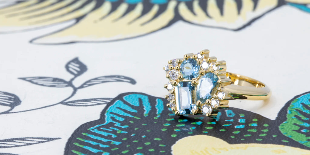 Aquamarine engagement ring by Pompei Fine Jewellery, available at Ruby Mardi. Featuring asymmetrical aquamarines and moissanites in a 14k yellow gold setting. A unique bridal ring photographed on an artistic background. Handmade and one-of-a-kind jewelry from Canada.