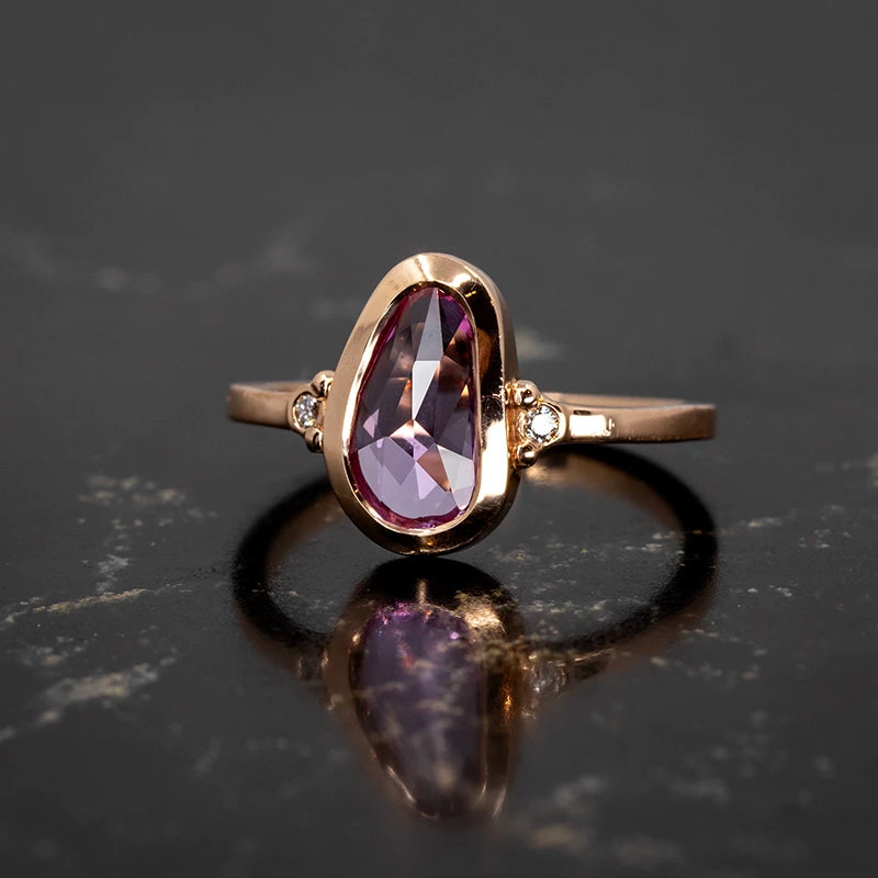 A captivating rose-cut pink sapphire ring set in a warm 14k rose gold bezel with delicate diamond accents on the band. Designed by Arsaeus Designs, this elegant piece combines vintage charm with modern craftsmanship. Available at Ruby Mardi, an independent jewelry boutique in Montreal offering custom designs.