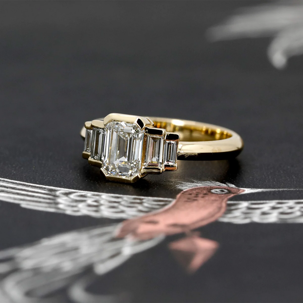 Art Deco emerald-cut diamond ring with baguette diamonds on each side, set in yellow gold. Handmade by independent designer and available at Ruby Mardi, fine jewelry store in Montreal, Canada.