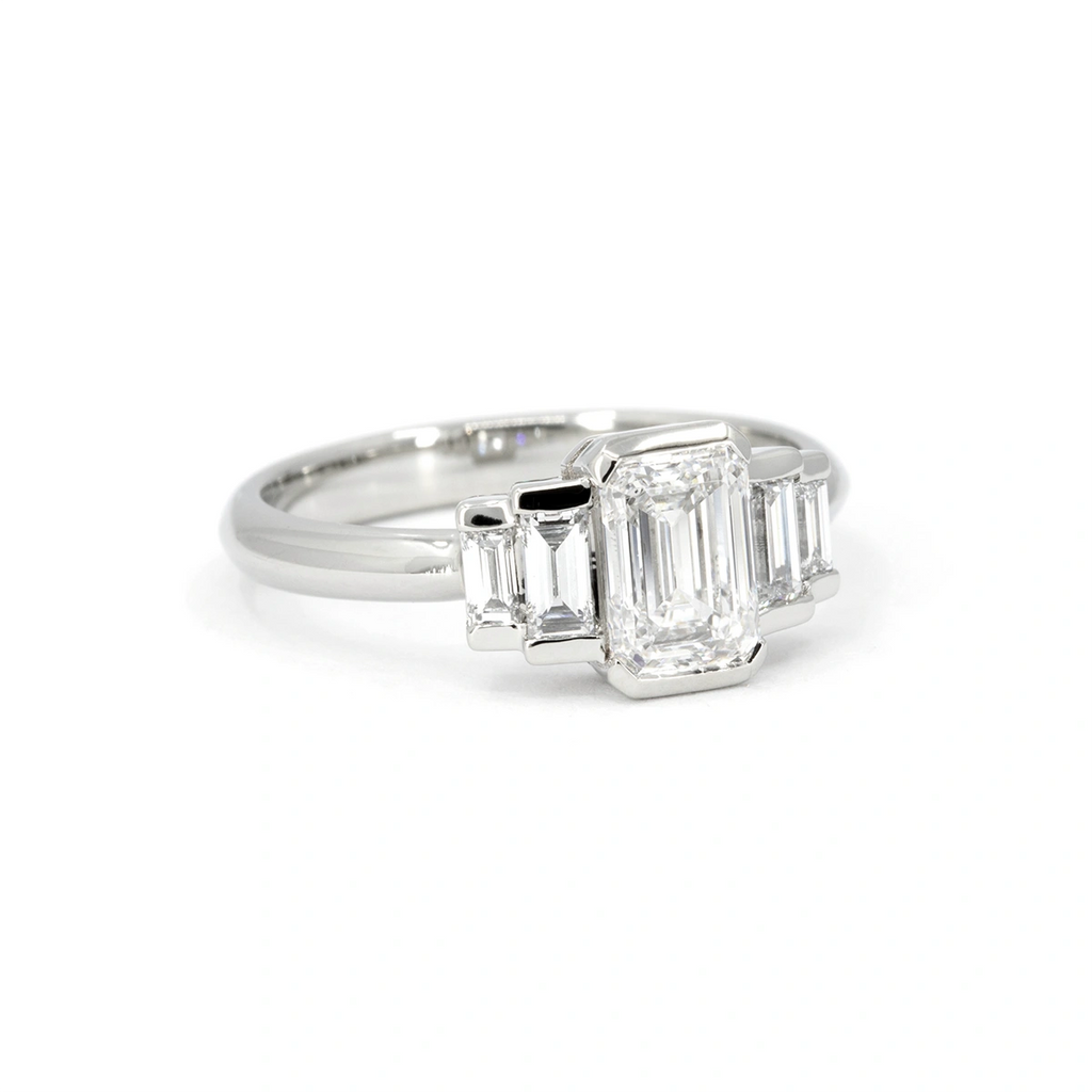 White gold engagement ring featuring an emerald-cut center diamond flanked by straight baguette diamonds in a symmetrical Art Deco-inspired layout. A bold and architectural design handcrafted in Montreal by Ruby Mardi. A modern heirloom for lovers of clean lines and graphic elegance.