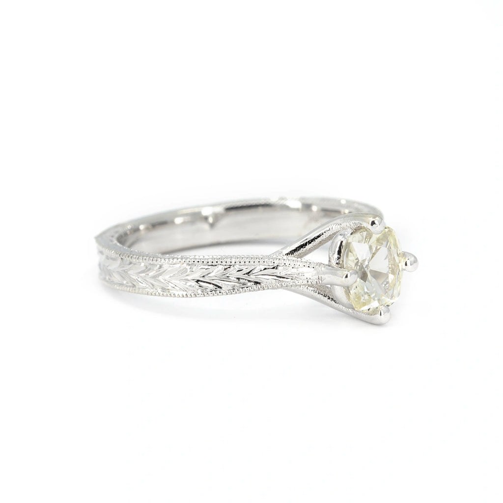 Side view of an Art Deco-inspired 14k white gold engagement ring with an oval pale yellow sapphire and intricate hand-engraved milgrain detailing. Designed by Deborah Lavery, available at Ruby Mardi, Montreal.