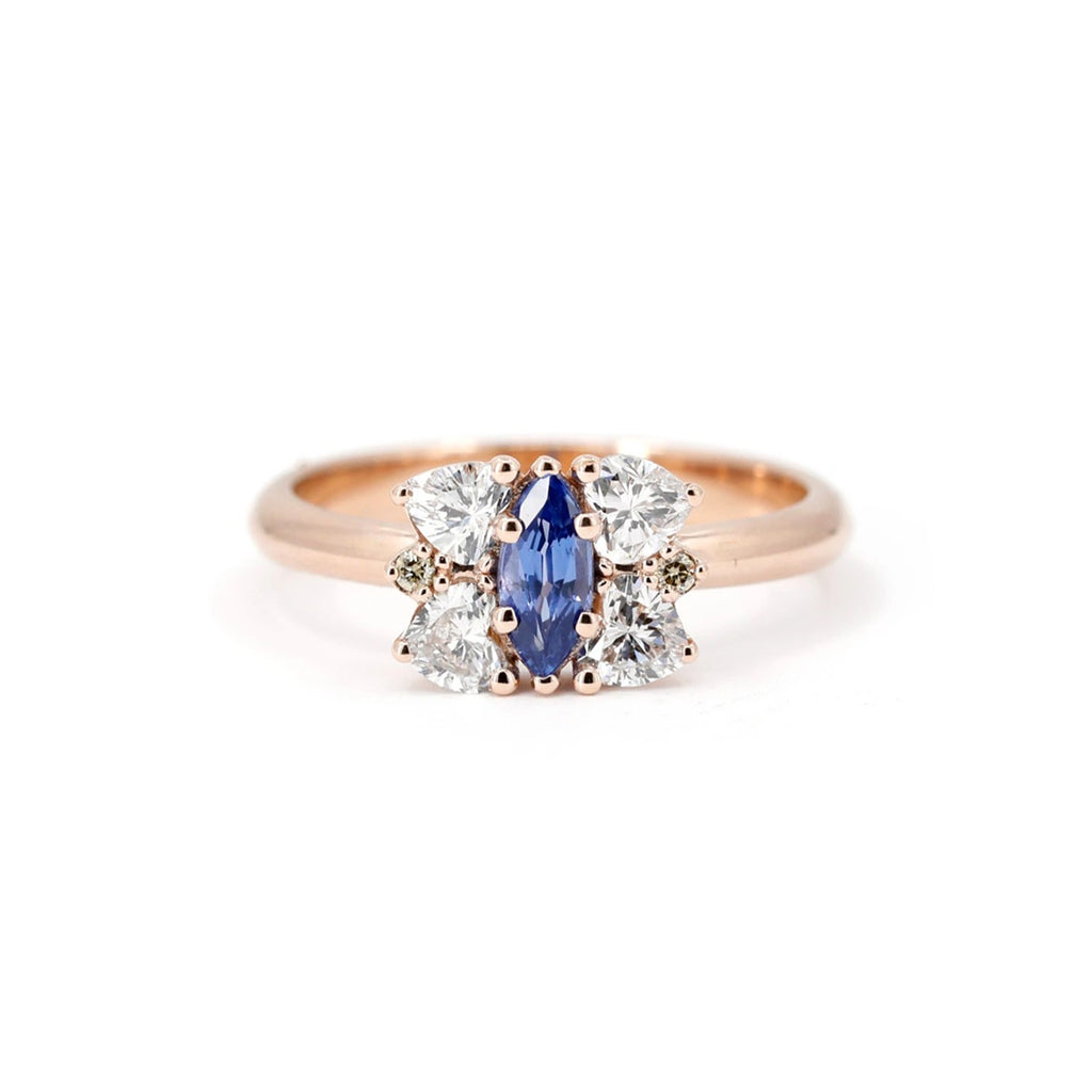 Front view of the Aurorina engagement ring in rose gold, showcasing a marquise blue sapphire surrounded by pear and round white diamonds. Ruby Mardi, Montreal.