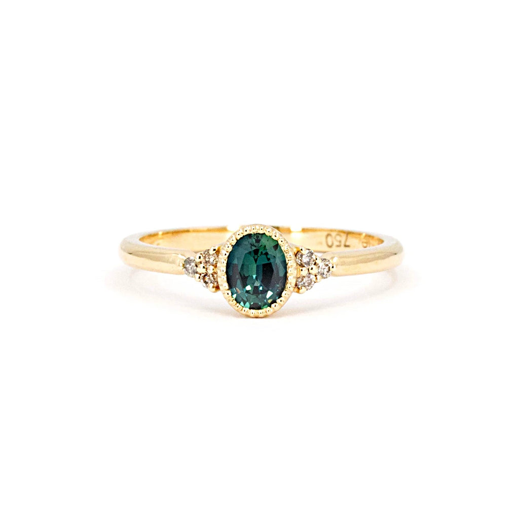 This splendid engagement ring with an oval-shaped teal sapphire, is a unique creation by the jewelry designer Emigé made in Quebec in collaboration with the Ruby Mardi jewelry store located in the Villeray and Rosemont district. This yellow gold ring is set with pretty natural diamonds.