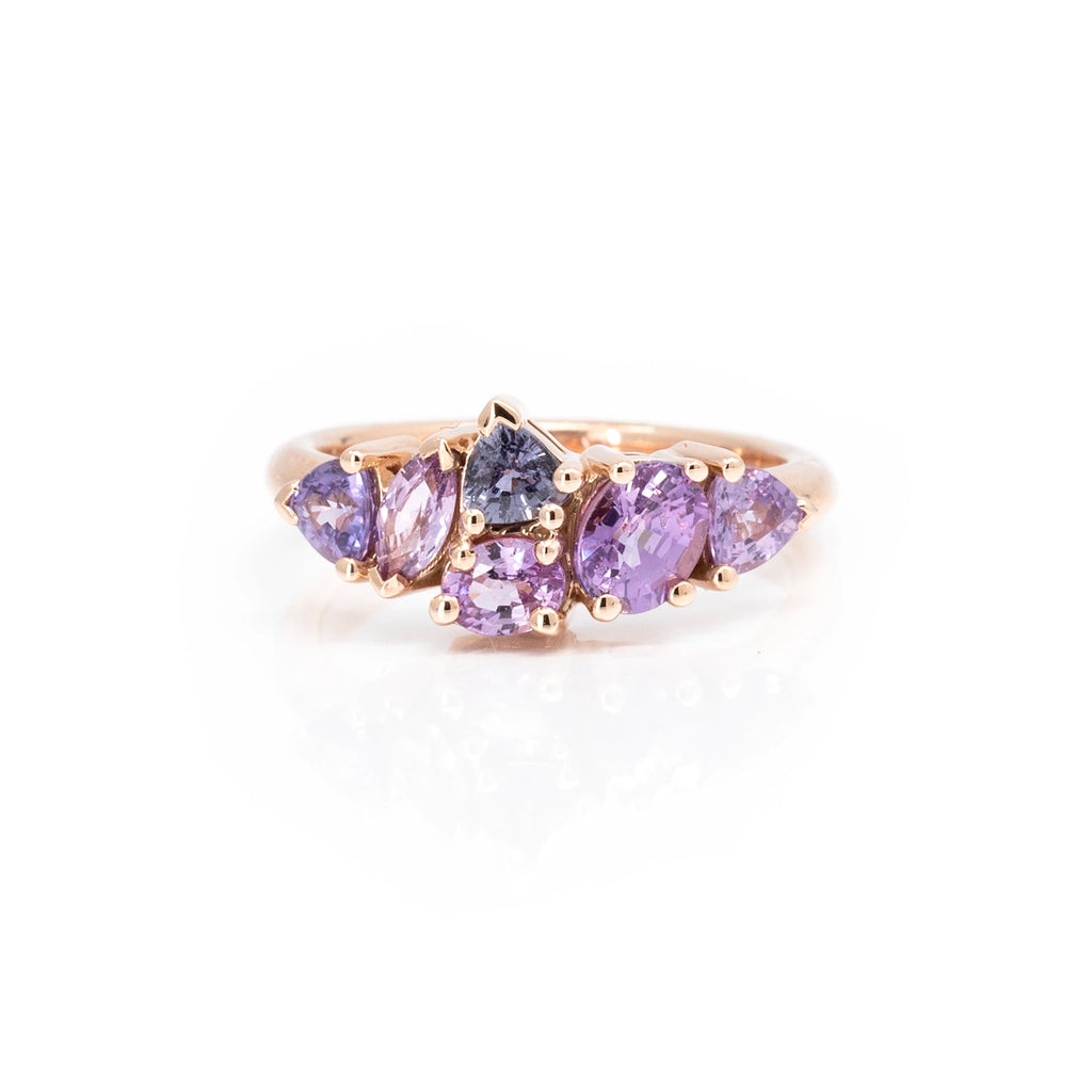 Funky alternative engagement ring featuring 6 natural sapphires in the shades of lilac and purple. The bridal ring is photographed on a white background. It's available in Montreal and online.
