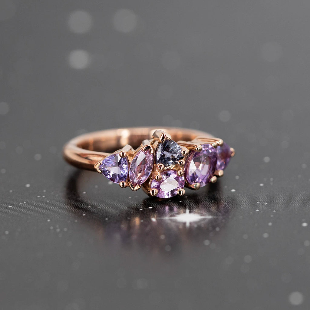 A beautiful rose gold ring featuring many small purple gemstones is photographed on an image evoking the twilight. This alternative engagement ring or right hand ring is available at jewelry store Ruby Mardi in Motnreal.