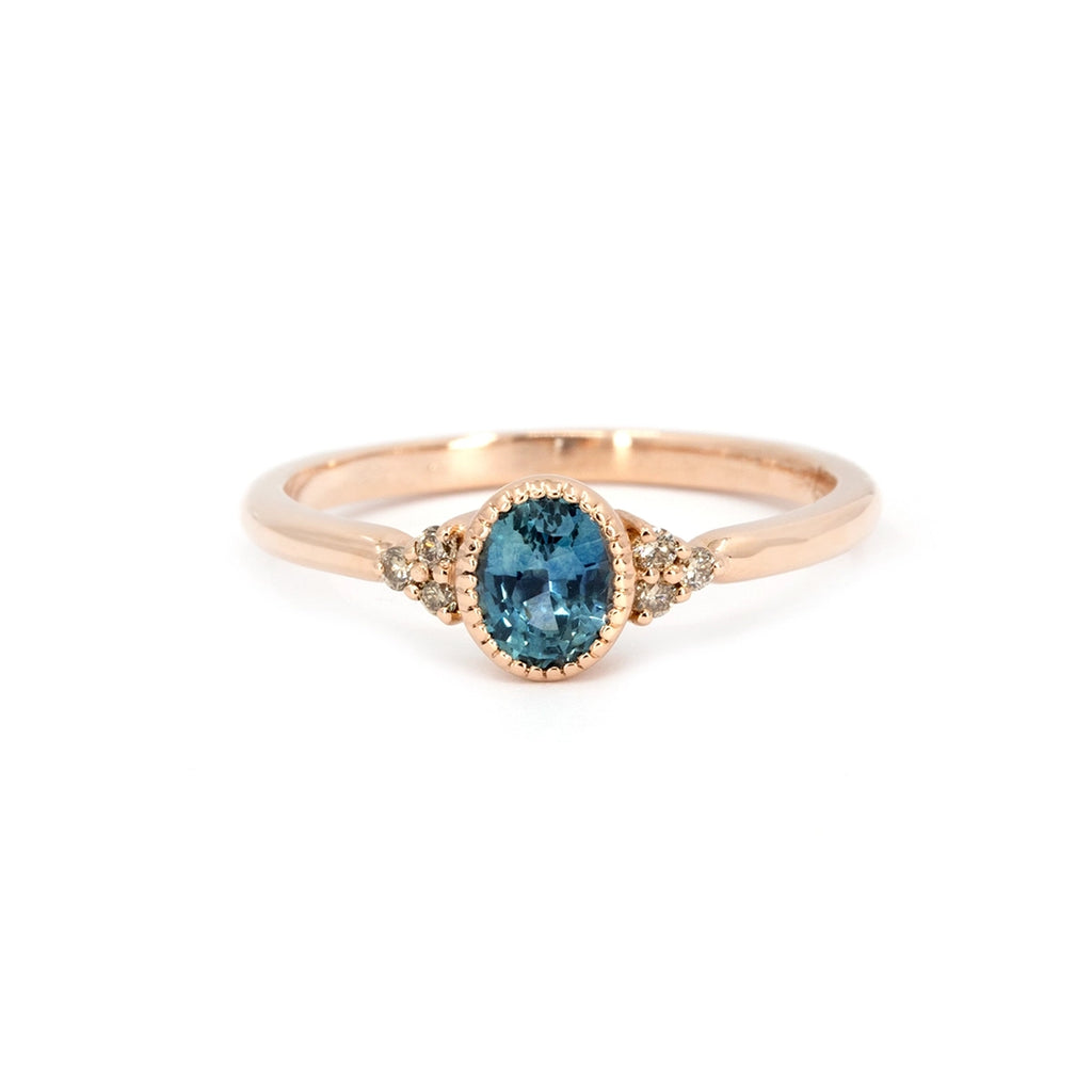 Rose gold engagement ring featuring an oval teal sapphire and champagne diamond accents, handcrafted in Montreal by Atelier Emigé for Ruby Mardi.