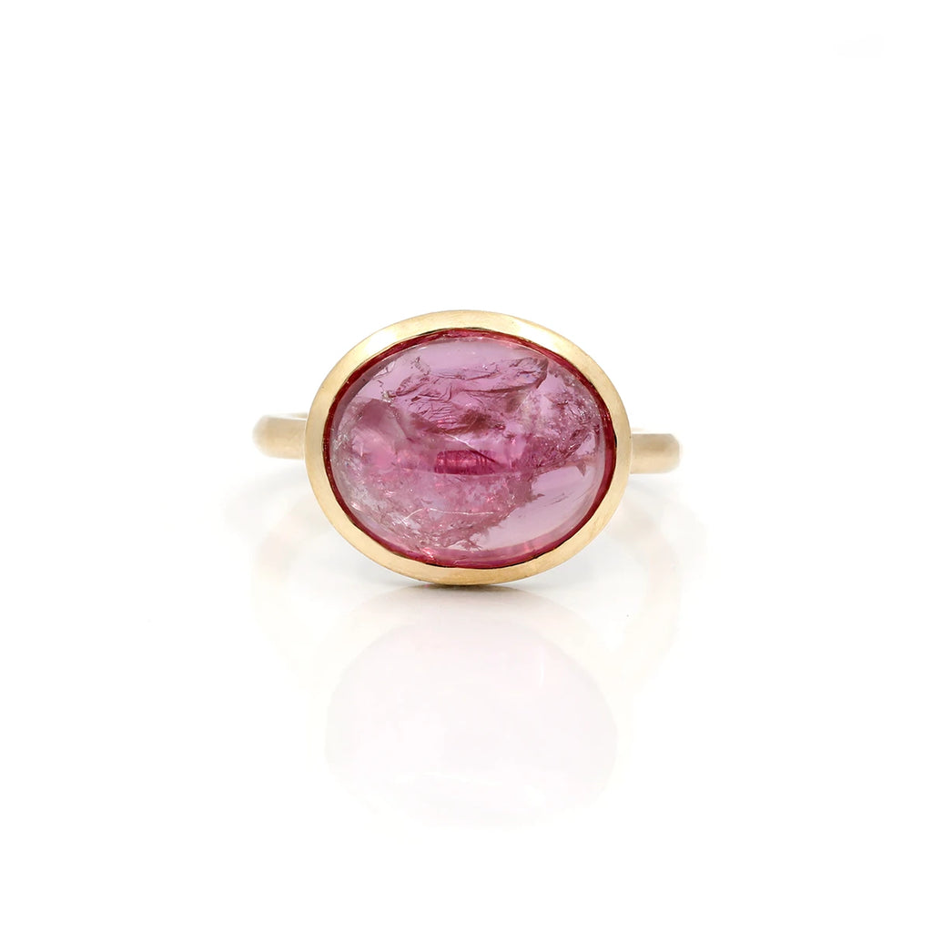 Big oval ruby cabochon gold ring seen from face and on a white background. The natural gemstone shows frost-like natural inclusions that makes it organic, or alive. It has something from outer space!