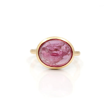 Big oval ruby cabochon gold ring seen from face and on a white background. The natural gemstone shows frost-like natural inclusions that makes it organic, or alive. It has something from outer space!