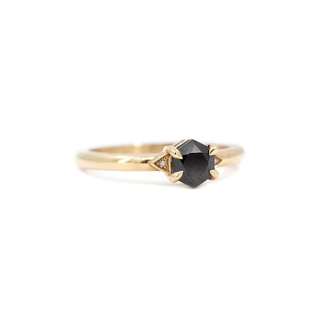 Close-up of the Luna Hex ring by Liane Vaz, featuring a hexagonal black spinel in hand-carved prongs with small champagne diamond accents, set on a polished yellow gold band. Ruby Mardi, Montreal.
