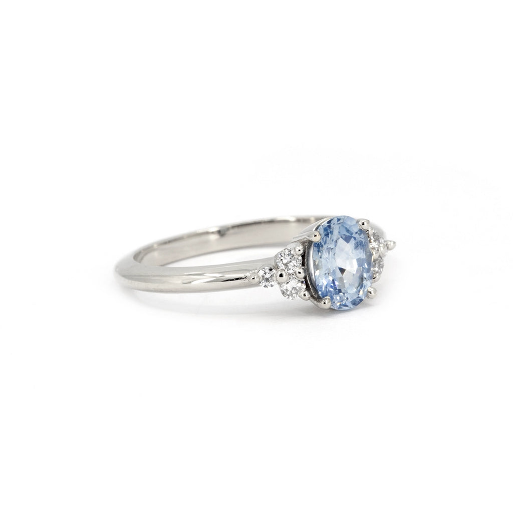 Side-angle view of a light blue sapphire engagement ring by Pompei Fine Jewellery, available exclusively at Ruby Mardi. This 14k white gold ring features an oval-cut sapphire with a delicate blue hue, accented by round brilliant lab-grown diamonds. A timeless and elegant design.