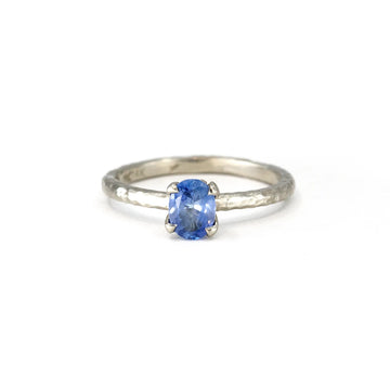 A delicate white gold engagement ring featuring a textured band and a stunning oval blue sapphire centerpiece. Handmade by Anouk Jewelry and available exclusively in Montreal at Ruby Mardi.