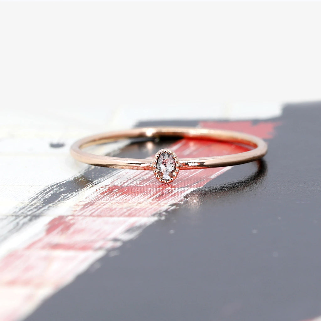 This delicate engagement ring made by independent jewelry designer Émigé in Montreal. Made in rose gold with a splendid oval salt and pepper diamond in rose cut, this bridal ring is delicate and refined for lovers of vintage jewelry. The central diamond is in a bezel setting surrounded by a delicate miligrain.