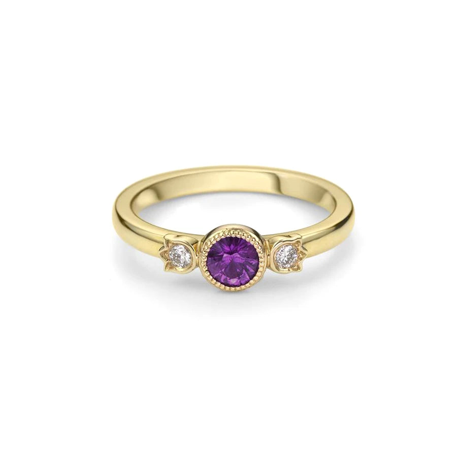Ruby Mardi presents the alternative engagement ring in yellow gold with a splendid natural sapphire in purple color and rectangular shape. Bezel set with a delicate miligrain, this bridal ring is made with two delicate diamonds around the central gem. This piece of jewelry is handmade by independent jewelry designer Bramston Goldsmithing in Canada.