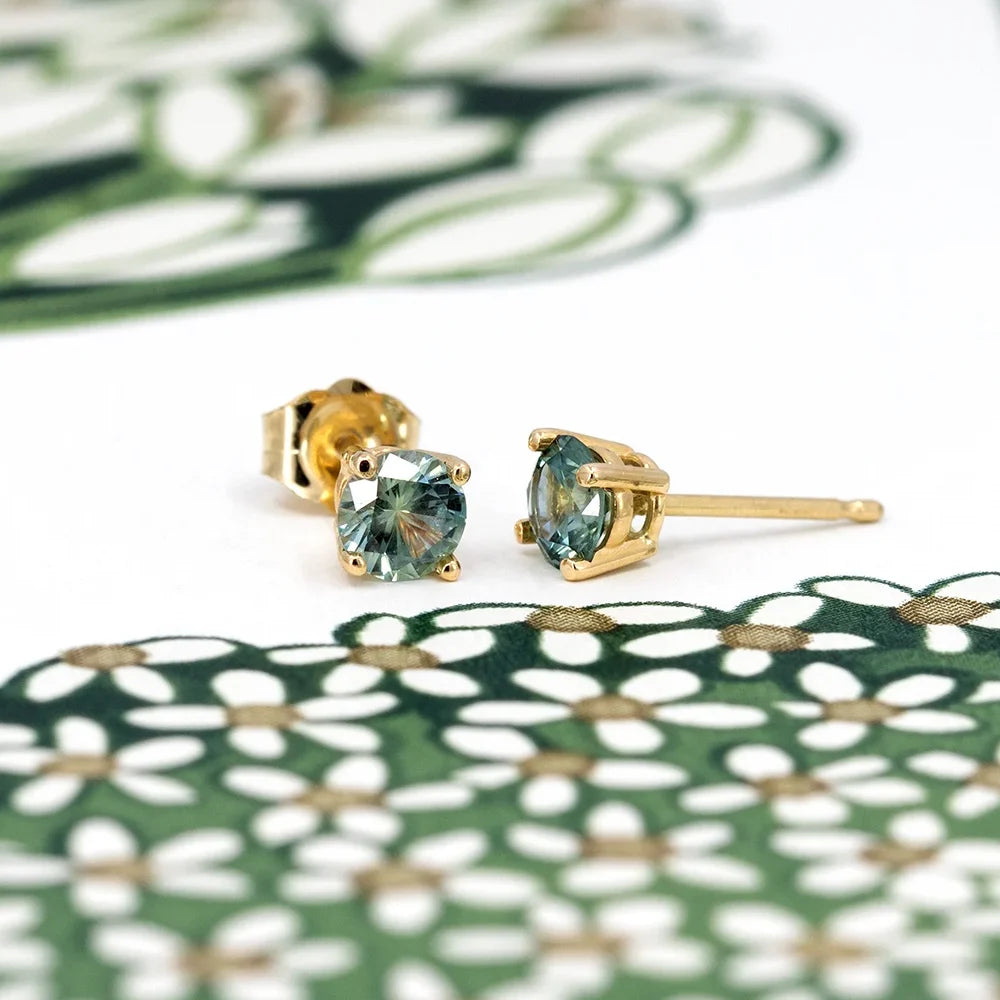 Elegant yellow gold stud earrings set with round brilliant cut Montana green sapphires, handcrafted by Meg Lizabet Jewellery, available at Ruby Mardi in Montreal.