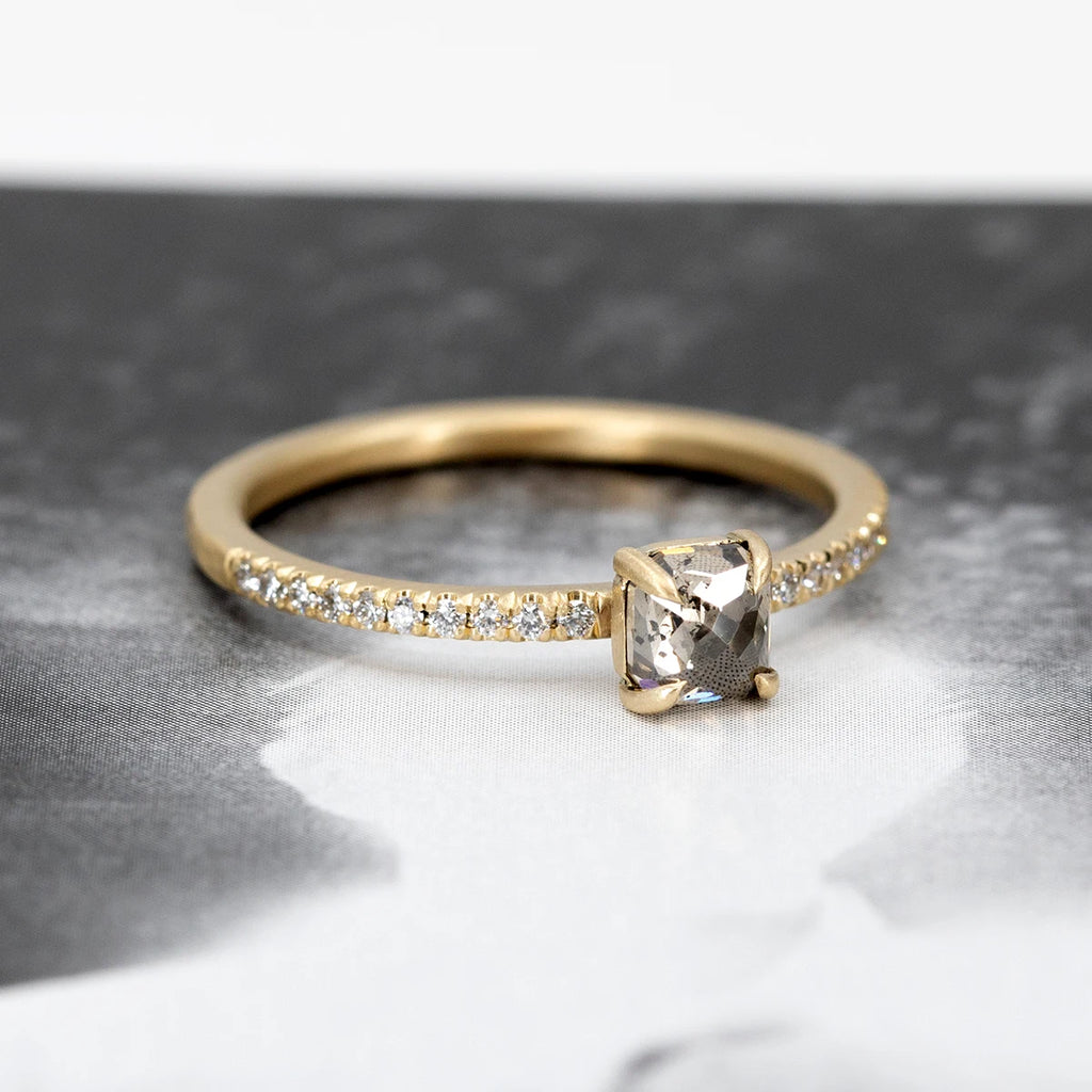 A classic solitaire engagement ring seen on an abstract black and white background. The delicate bridal ring is set with small round brilliant diamonds, in half eternity. This ring in 14k yellow gold was handcrafted in Canada by Fluid Jewellery. This video was filmed and edited by Ruby Mardi, the coolest jewelry store in Canada, that sells the jewels from indie Canadian jewelry designers, as Gem Breakfast does in the USA. 