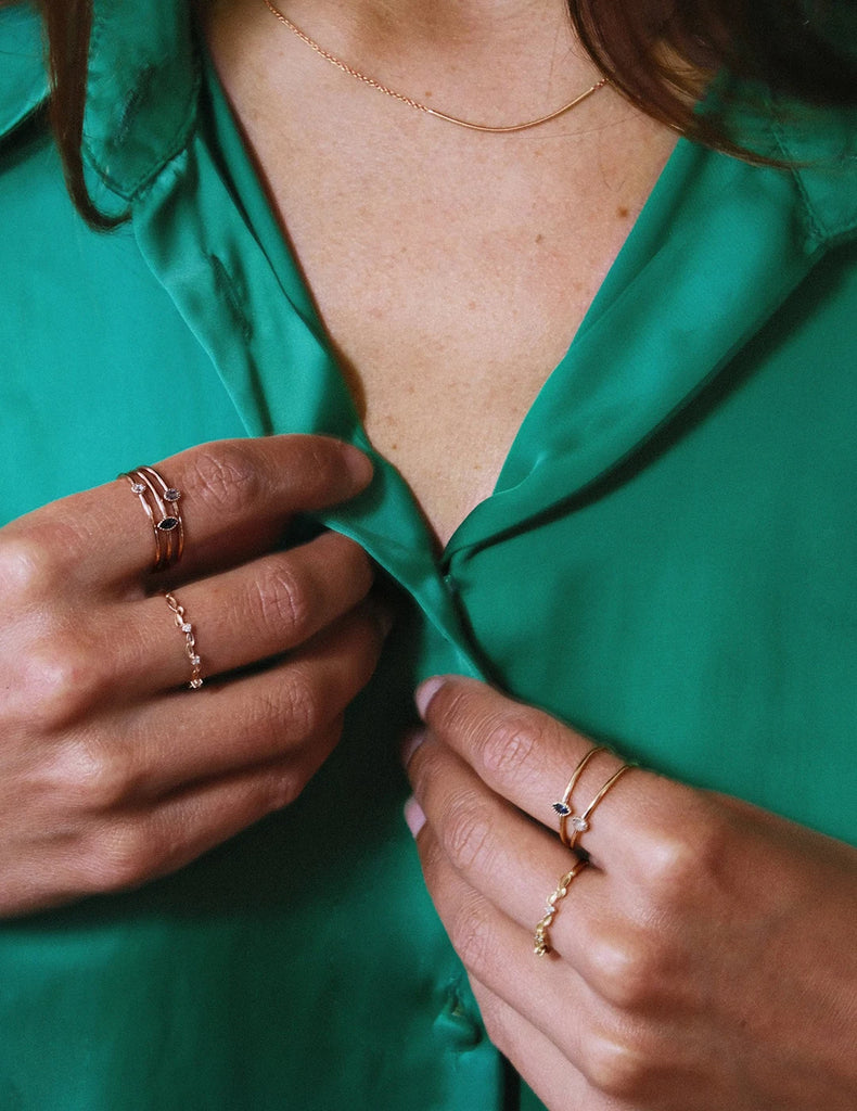 Young woman wearing engagement rings and wedding band on several fingers of her hand. These bridal jewelry are minimalist with different types of colored gems and round, rose cut or marquise shaped diamonds. These alternative and original fine jewelry are available at the best jewelry store in Montreal Ruby Mardi.
