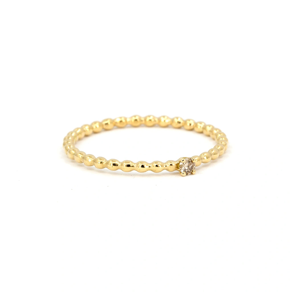 Dainty yellow gold ring with beaded band and small champagne diamond solitaire, photographed on a white background. Handmade by Atelier Emigé, available at Ruby Mardi, a cool jewelry store in Montreal.