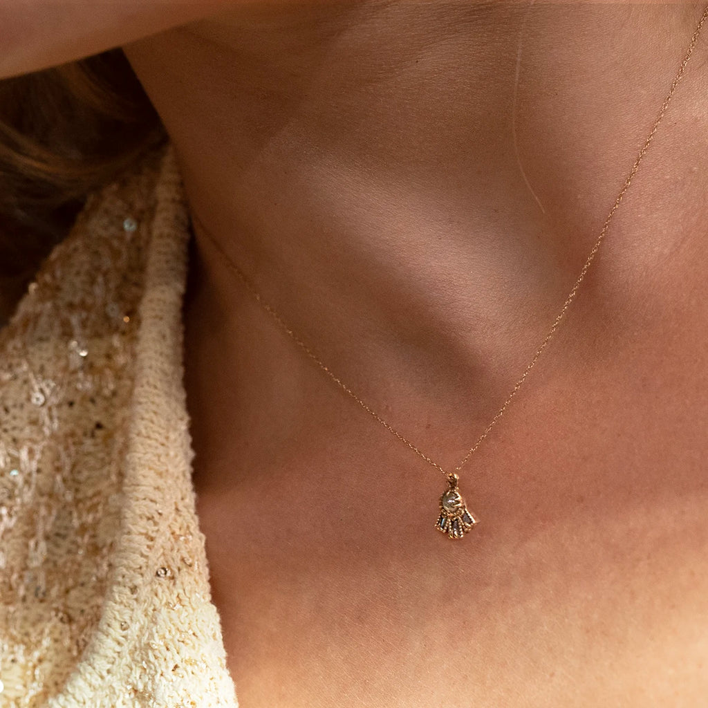 Gold necklace with a small diamond cabochon pendant in the shape of a stylized hand, worn on a woman’s neck. Designer jewelry by Ruby Mardi, Montreal, Canada.