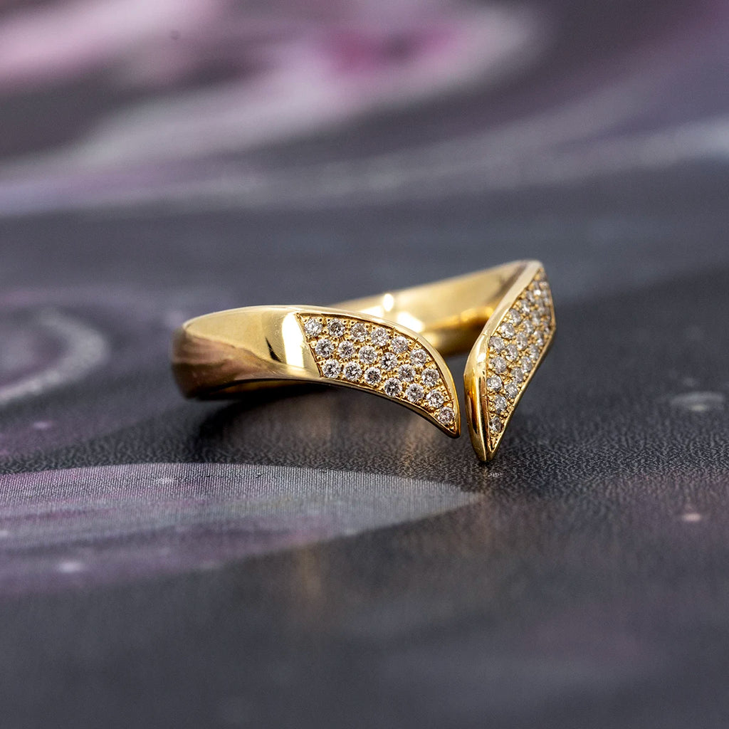 V-shaped diamond band in solid 10k yellow gold by Canadian jeweller Nadia Werchola, shown on a dark textured surface. The front of the ring is fully pavé-set with lab-created diamonds, highlighting its bold open design and luminous contour.