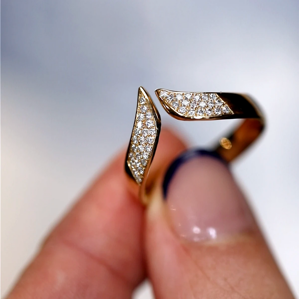 Close-up of a V-shaped diamond band in solid 10k yellow gold by Canadian jeweller Nadia Werchola, held between fingers. The front of the ring is fully pavé-set with lab-created diamonds, highlighting the bold open design and tapered tips against a soft blurred background.