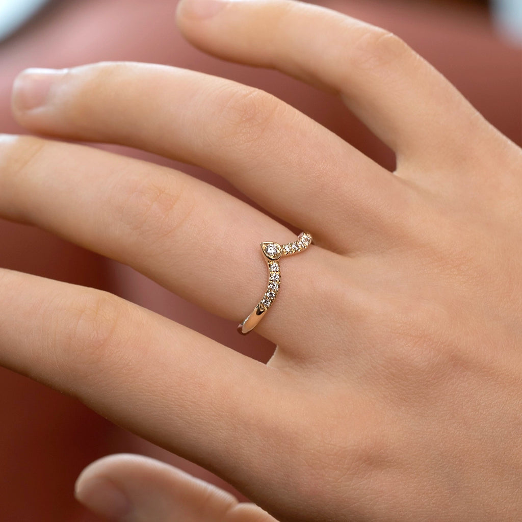 14k yellow gold diamond wave wedding band by Toronto designer Yuliya Chorna, shown worn on the hand. Elegant crown-style band with pavé diamonds and a pear-shaped gold detail holding a round diamond at the peak. A modern and original wedding ring that pairs beautifully with engagement rings or shines on its own, available at Ruby Mardi.