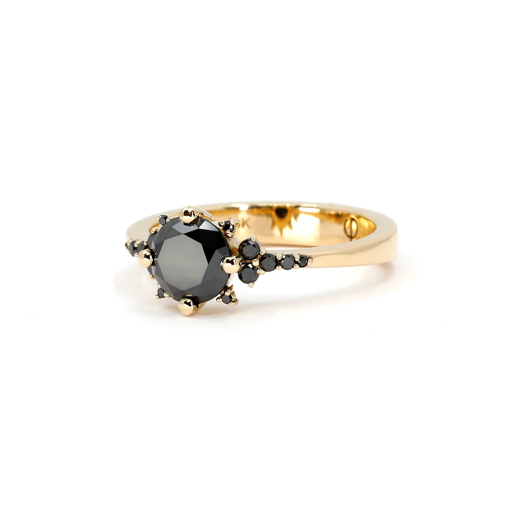 The Éclipse ring, an elegant 14k yellow gold design featuring a captivating round-cut black diamond at its center. Accentuated by a delicate arrangement of smaller black diamonds and gold bead detailing, this celestial-inspired piece exudes mystery and sophistication. Available at Ruby Mardi, an independent jewelry boutique in Montreal offering custom jewelry services.







