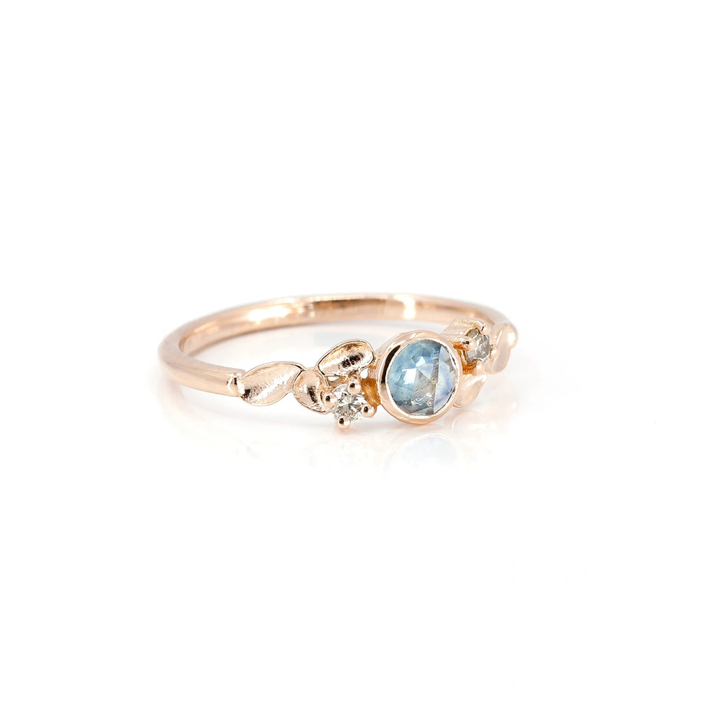 Ruby Mardi jewelry presents the alternative and elegant engagement ring from independent Montreal jewelry designer Émigé. Made in pink gold with a bezel-set rose-cut blue sapphire gem, complemented by two champagne diamonds, this bridal jewel is a unique creation and handcrafted in Canada.