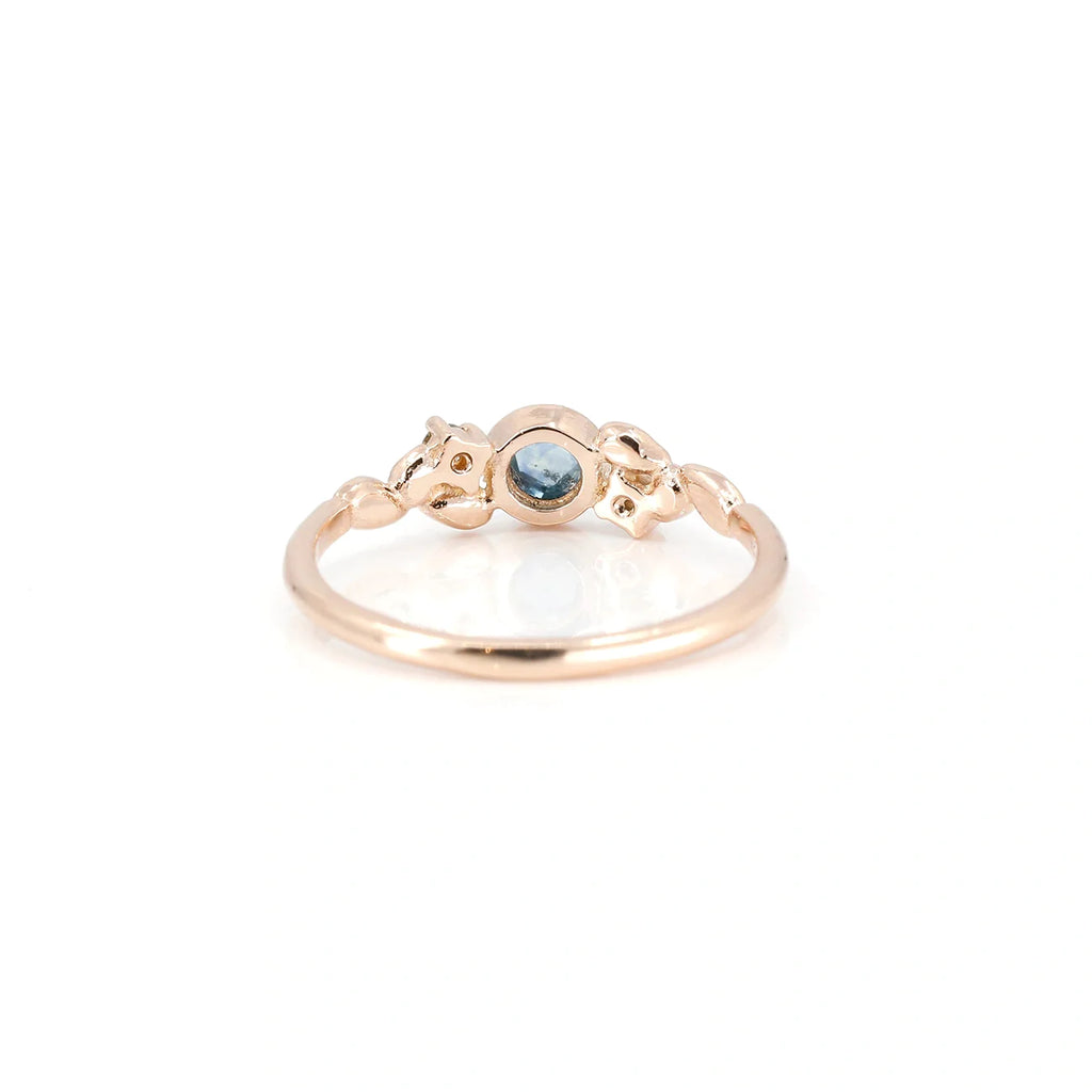 The rear view of this rose gold engagement ring reveals the bezel setting of the rose cut sapphire. This bridal jewelry with a natural blue gem and diamonds is made by the independent designer Émigé in her Montreal studio, in partnership with the fine jewelry store Ruby Mardi which offers wedding rings and delicate jewelry made in Canada.