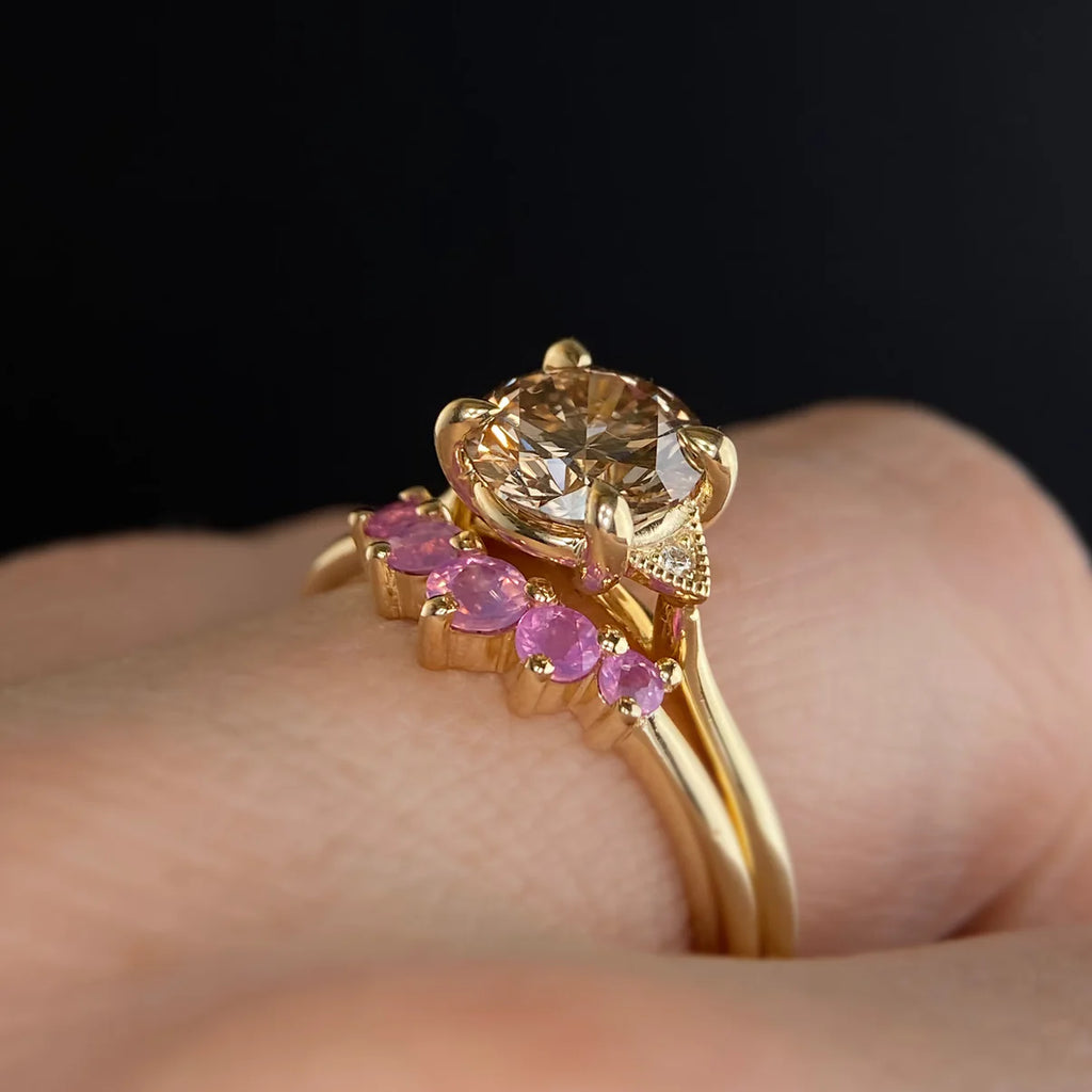 Wedding ring stack featuring a champagne sapphire engagement ring paired with a pink sapphire contour band in 14k yellow gold. Handmade by Emily Gill, available at Ruby Mardi, Montreal.