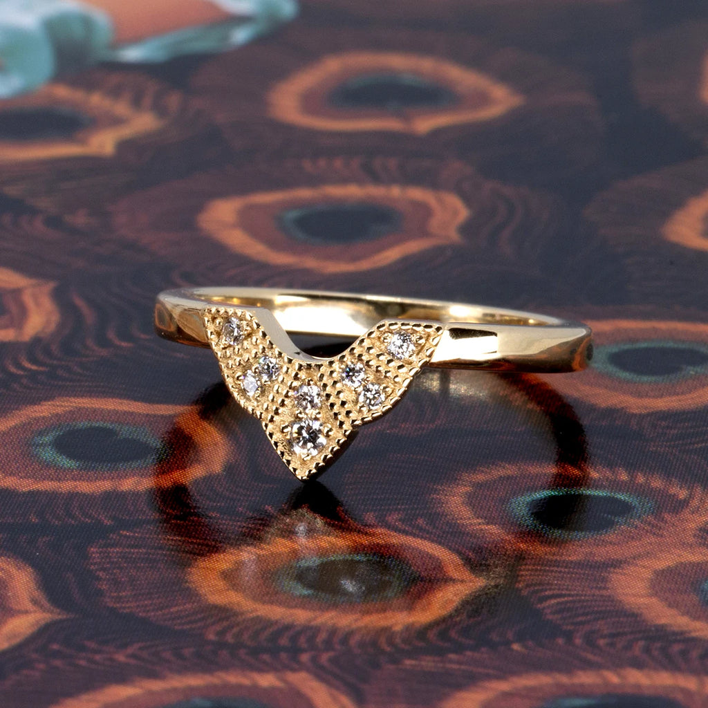 Art Deco-inspired V-shaped gold ring with natural diamonds and milgrain detail, designed by Deborah Lavery in Toronto for Ruby Mardi. Photographed on a peacock feather print background.
