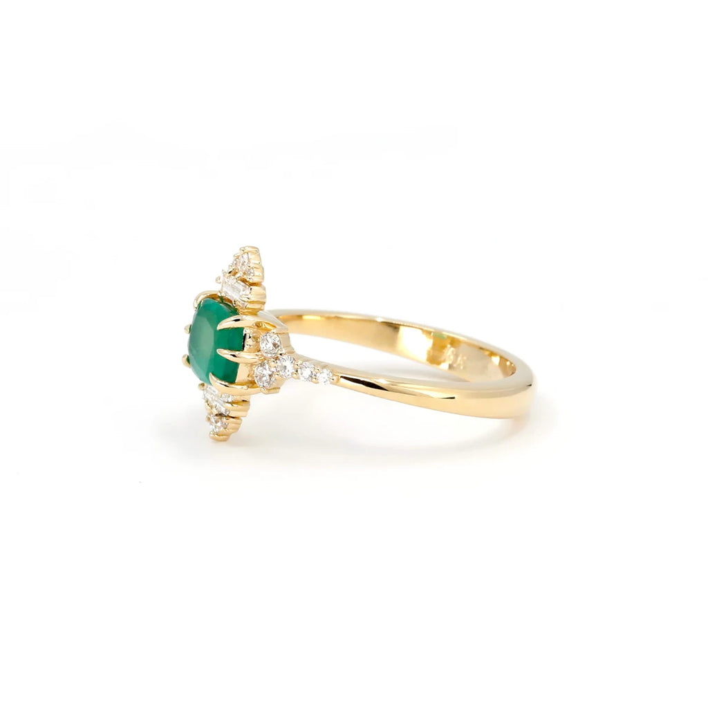 The side view of this yellow gold wedding ring with a vivid green emerald gem is made by Canadian independent jewelry designer Oleg Leybman. Made in yellow gold with natural diamonds with spade-shaped prongs. This ring is available for sale at the Ruby Mardi jewelry store located in Montreal and specialized in fine jewelry.